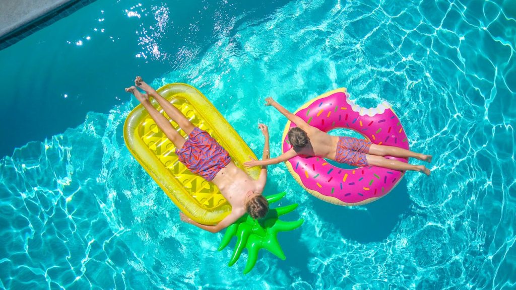 aerial view of two children on inflatable floating devices in pool
