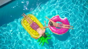 aerial view of two children on inflatable floating devices in pool