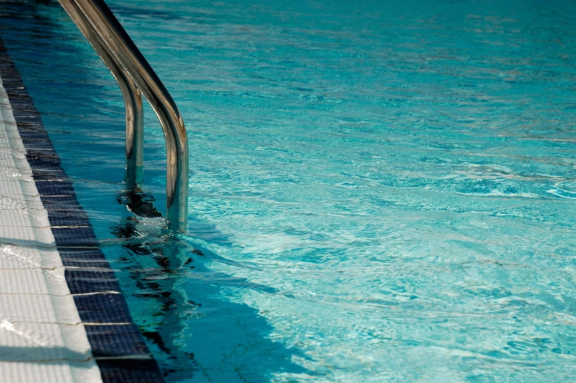 A step ladder leading into the blue water of a swimming pool