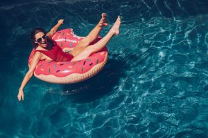 Woman floating in donut pool toy in poo