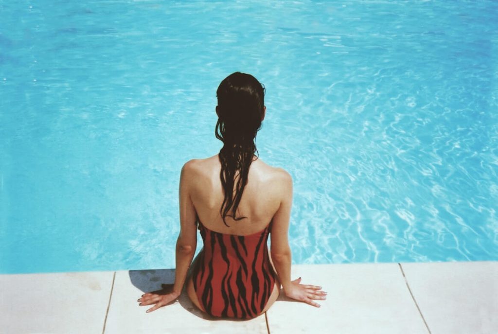A person relaxing by the side of a pool with their hair wet